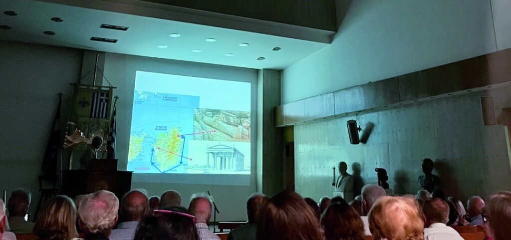 Εικ. 2. Ο κ. Κορρές δείχνει στον χάρτη της Νάξου την θέση των λατομείων και τις διαδρομές που ακολουθούσαν για την μεταφορά των μαρμάρων για τον χώρο επεξεργασία ή και τοποθετήσεως 